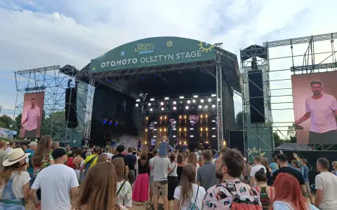 Tłum na festiwalu, na scenie OTOMOTO OLSZTYN STAGE. Kim Nowak w piasku, wśród ludzi.