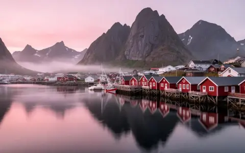 Drömmen om att **bila till Lofoten** blir verklighet vid denna pittoreska hamn med röda fiskebodar och majestätiska berg.