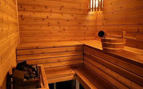 Drewniana sauna z kamieniami i wiadrem. Inspiracja, jak zbudować saunę, by cieszyć się relaksem.