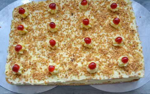 Rechteckiger Frankfurter Kranz Kuchen, bestreut mit gehackten Nüssen und verziert mit Sahnetuffs und Kirschen. Sally liebt diese Schnitten!