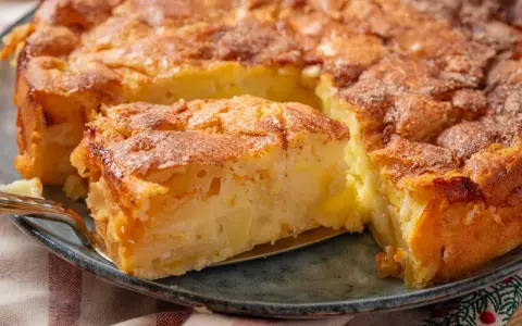 Ein goldbrauner Apfelkuchen mit Zimtstreuseln, der Lust auf tolle Apfelkuchen Rezepte macht. Ein Stück wird gerade herausgehoben.