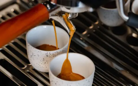 Frisch gebrühter Espresso fließt in zwei Tassen. Hoffentlich schmeckt er nicht zu sauer.