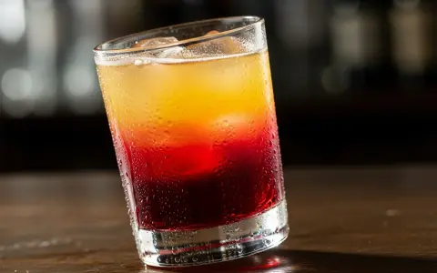 En kyld Alabama Slammer-drink med lager av rött och gult, perfekt för en varm dag.