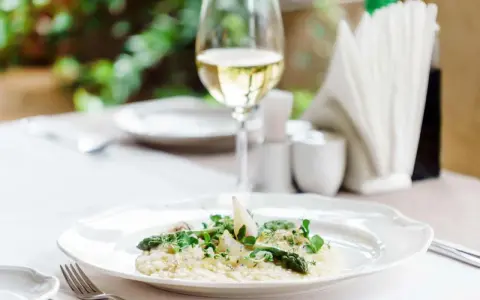 En krämig risotto med sparris och örter, perfekt ackompanjerad av ett glas vitt vin till risotto.