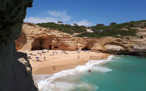 Sonniger Strand an der Algarve, ein echter Geheimtipp mit Felsformationen und türkisfarbenem Wasser. Menschen entspannen sich am Sandstrand.