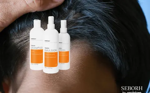 Trzy białe butelki z pomarańczowymi etykietami: szampon, emulsja i lotion SEBORH. Pomagają w walce z łzs.
