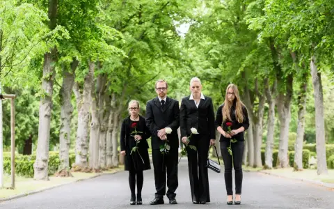 Rodzina w żałobie, każdy z różą. Ojciec w garniturze, matka i córki w czarnych strojach. Odpowiednia koszula na pogrzeb to podstawa.