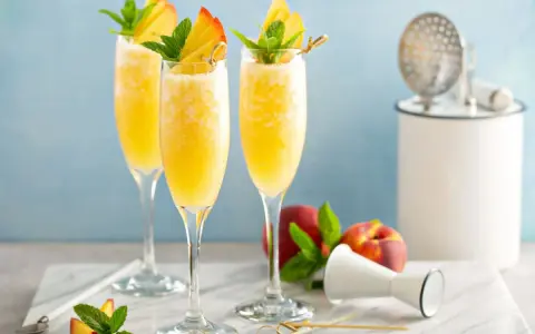 Orzeźwiający drink z prosecco i sokiem pomarańczowym, udekorowany brzoskwinią i miętą. Idealny na letnie popołudnie.
