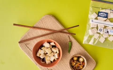 Vorbereitung für tofu einfrieren: gewürfelter Tofu in Schüssel mit Soße, daneben Stäbchen, Chili und ein Gefrierbeutel mit Tofuwürfeln.
