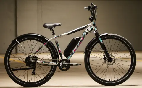 A white GT power performer electric bike with a colorful geometric pattern, parked indoors.
