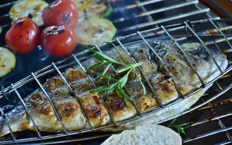 Dorade au barbecue, grillée à la perfection avec des tomates et des courgettes. Une branche de romarin parfume ce plat savoureux.