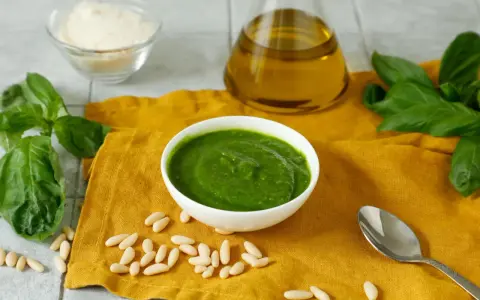 Una ciotola di pesto fresco, pinoli, basilico, parmigiano e olio d'oliva, ingredienti perfetti per una deliziosa pasta al pesto.