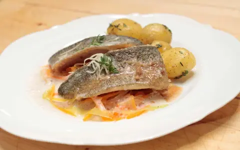 Zartes Forellenfilet braten, serviert mit kleinen Kartoffeln und julieniertem Gemüse in einer leichten Sauce. Ein Genuss!
