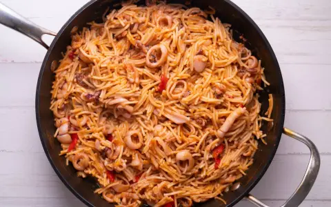 Fideuà de marisco en paellera, con fideos finos, calamares y pimientos rojos. ¡Perfecta para aprender como hacer fideuà!