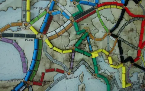 Planszowa mapa Europy z kolorowymi wagonikami. Która trasa jest najlepsza, by wsiąść do pociągu i odkryć nowe miasta?