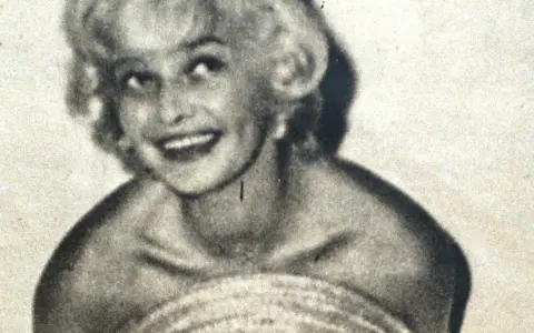 Uśmiechnięta Marilyn Monroe, ikona kina, w czarno-białym ujęciu. Jej imię zna cały świat.