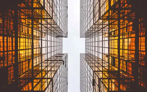 Looking up between four golden glass buildings, the architecture forms a cross shape, resembling a modern church.