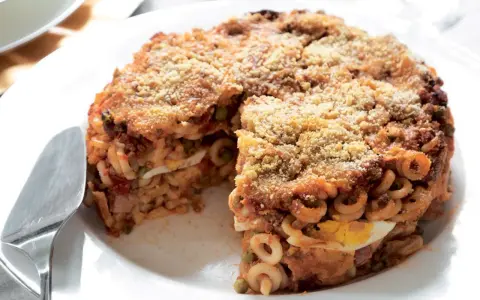 Un invitante anelletti al forno, con strati di pasta, sugo, piselli e uova sode, ricoperto da pangrattato dorato.