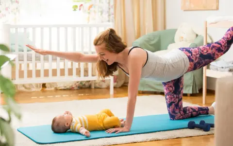 Mama wykonuje ćwiczenia po porodzie na macie, a jej maluch leży obok.