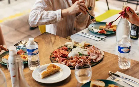 Un plateau de charcuterie et fromages, une spécialité provençale, partagé autour d'une table ensoleillée.