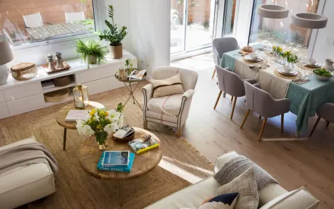 Espacio luminoso con sofás, mesas de centro y una mesa de comedor lista para una comida. La distribución del comedor es funcional y acogedora.