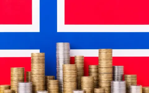 Stosy monet na tle flagi Norwegii symbolizują oszczędności i przyszłość, być może związane z wiekiem emerytalnym w Norwegii.