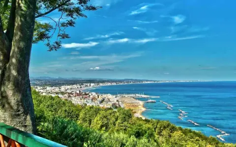 Vista panoramica della Riviera Romagnola con mare azzurro, spiagge affollate e una città costiera. Ideale per il turismo.
