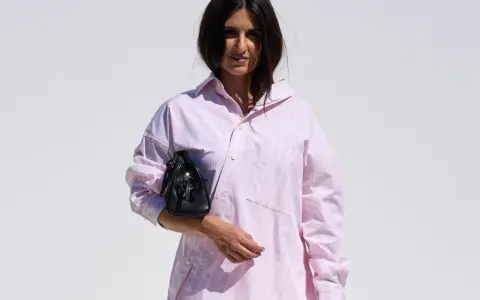 Mujer con una camisa rosa a rayas y un bolso negro.