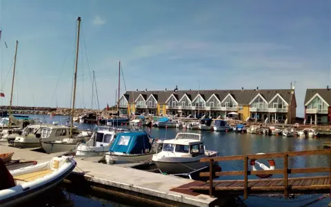 Port z łodziami i domkami w tle. Planujesz podróż rowerem na Bornholm? Koszty mogą być różne, ale widok jest wart każdej ceny.
