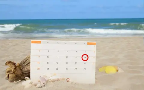 Kalendarz na plaży z zaznaczonym 14. dniem. Czas na urlop bezpłatny i relaks nad morzem.
