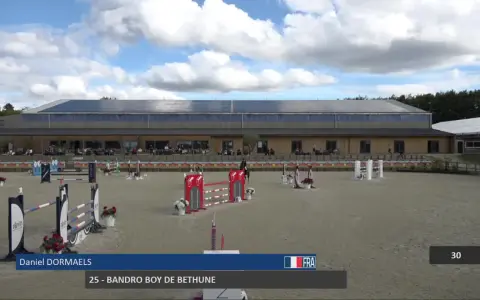 Daniel Dormaels et son cheval 25 - Bandro Boy de Bethune s'élancent sur la piste d'obstacles sous un ciel nuageux.