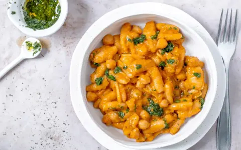 Herzhaftes Pasta e Ceci mit Kichererbsen in cremiger Sauce, garniert mit frischer Petersilie. Daneben eine kleine Schale mit Kräuteröl.