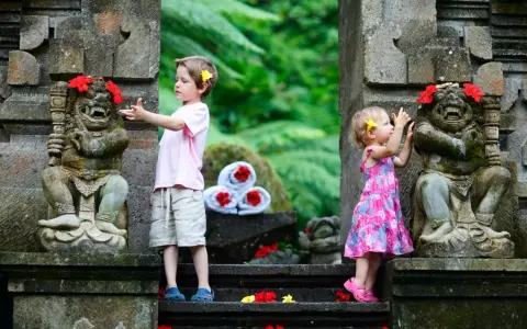 Bambini a Bali esplorano antiche statue decorate con fiori. Un'avventura indimenticabile per i più piccoli.