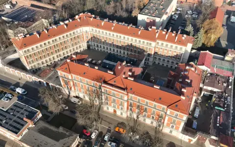 Widok z lotu ptaka na budynki więzienia aś montelupich. Czerwone dachy, białe fasady, dziedziniec z samochodami i drzewami.