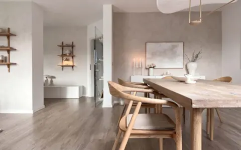 Interni in stile wabi sabi con tavolo in legno grezzo, sedie in legno chiaro e decorazioni minimaliste.