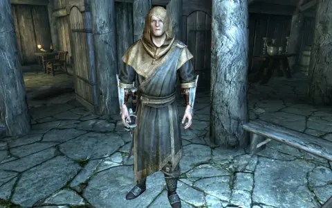 Un personaje con túnica y capucha en Skyrim, listo para curar el vampirismo.