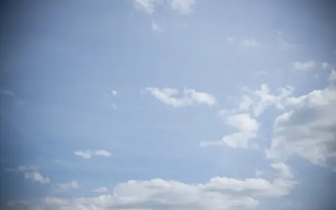 Jasne niebo z chmurami, efekt winietowania przyciemnia brzegi kadru, tworząc wrażenie głębi.