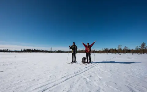 Två skidåkare njuter av en solig dag i Koppången naturreservat.