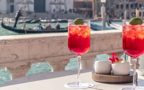 Deux Spritz vénitiens rafraîchissants sur une terrasse avec vue sur les canaux de Venise et les gondoles.