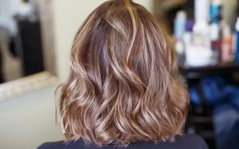 Piękne, falowane brązowe włosy z subtelnymi blond refleksami, które dodają im głębi i blasku.