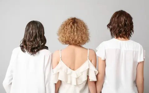 Trzy kobiety z tyłu. Jedna ma falowane, ciemne włosy, druga krótkie, kręcone blond włosy w stylu boho, trzecia falowane, brązowe włosy.