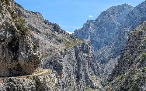 Wąska ścieżka wzdłuż skalnej ściany, część szlaku Ruta del Cares, prowadzi przez surowe, górskie krajobrazy.