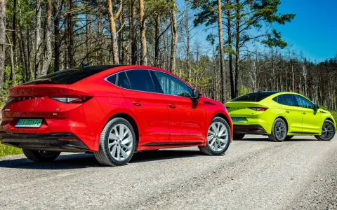 Dwa samochody Skoda Enyaq w kolorach czerwonym i limonkowym na leśnej drodze.