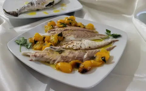 Orata in friggitrice ad aria, servita con pomodorini gialli e prezzemolo. Un piatto leggero e gustoso.