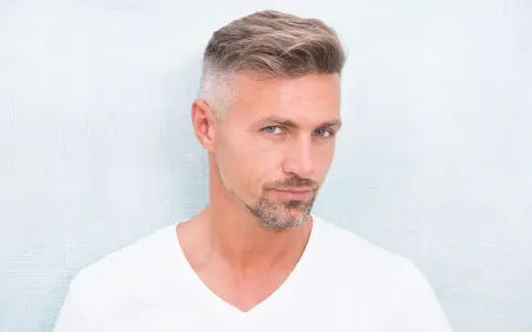 Hombre con barba corta y cabello peinado, luciendo un estilo moderno. Decidió dejarse perilla para un look más definido.
