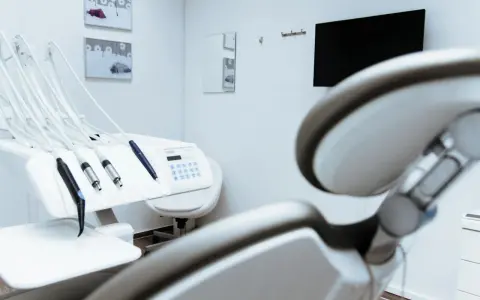 Gabinet stomatologiczny z fotelem i narzędziami. W tle monitor i lustro. Czystość i sterylność, jak po użyciu środka z chlorheksydyny diglukonianem.