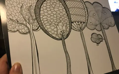 En hand håller ett papper med en detaljerad doodle av fantasifulla träd. Varje träd har unika mönster i kronorna, som om någon ville skapa doodle-konst.