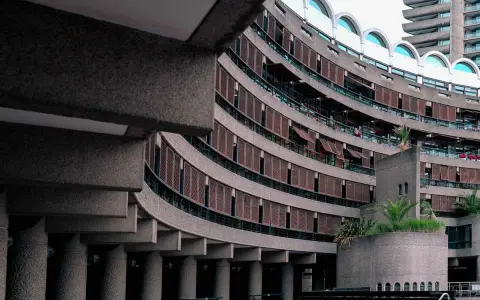 Edifici curvi in cemento con persiane in legno al Barbican Centre. Un'architettura iconica che si staglia nel cielo.