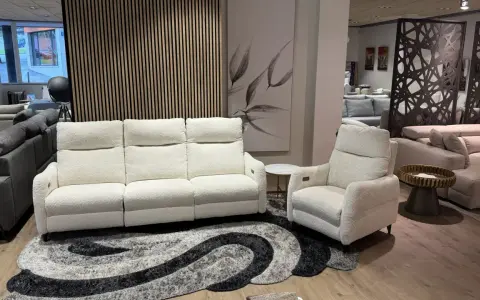 Sofá blanco de tres plazas y butaca a juego, perfectos para combinar sofá y butaca en tu salón. Alfombra moderna y cuadro decorativo.