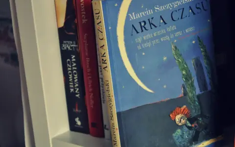 Książka "Arka Czasu" Marcina Szczygielskiego na półce. Ilustracja przedstawia nocne niebo z księżycem i biegnącą postacią.